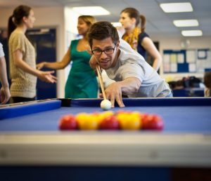 Student playing pool in student lounge