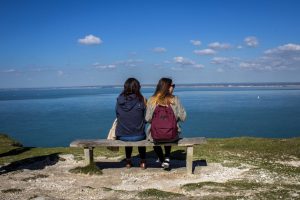 2 LSI/IH Portsmouth friends sitting on a bench together.