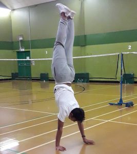 LSI/IH Portsmouth student does a hand stand at Badminton game.
